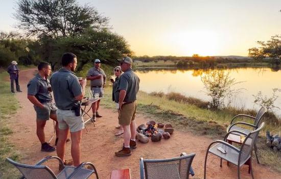 Hunters around the fire at sunset by the dam