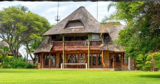 Main thatched lodge building on a green lawn